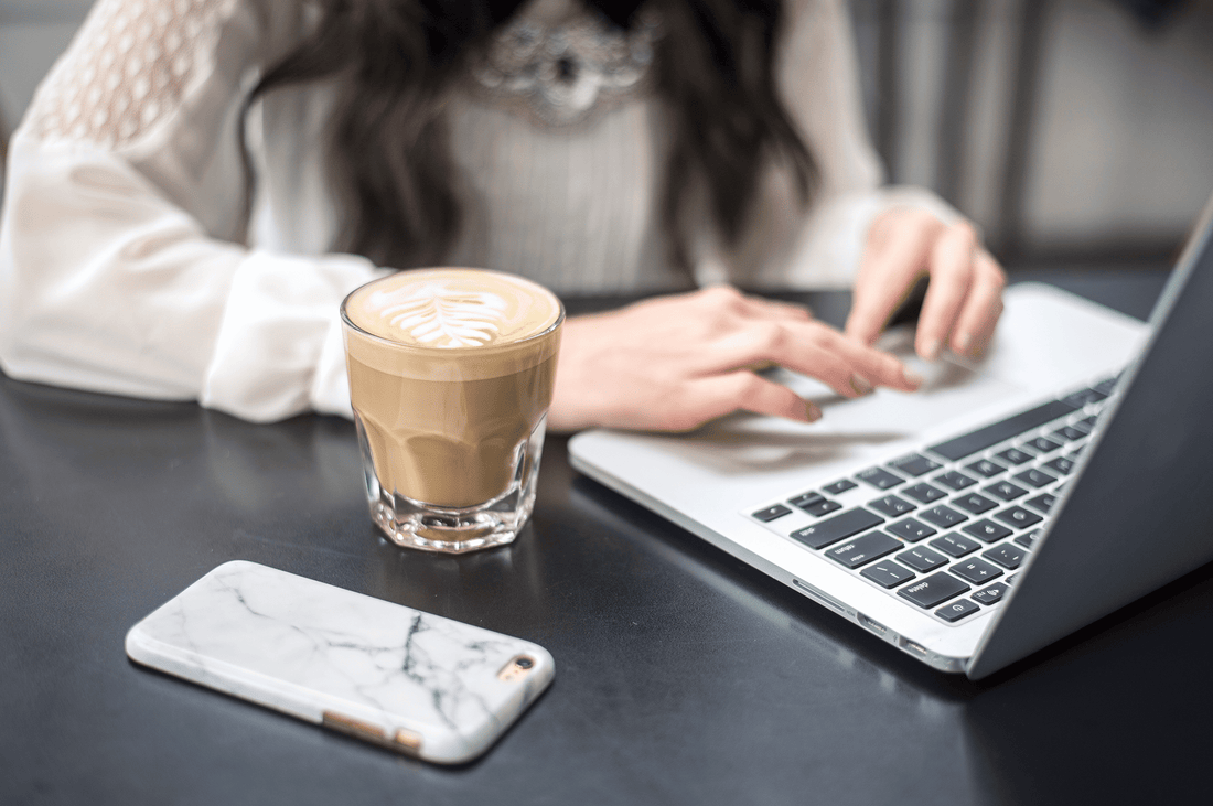 hands using keyboard with coffee next to laptop